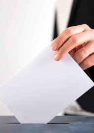 Hand of a voter putting vote in the ballot box. Election concept.