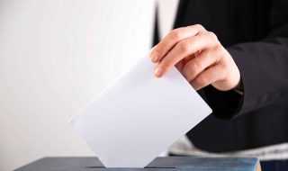 Hand of a voter putting vote in the ballot box. Election concept.